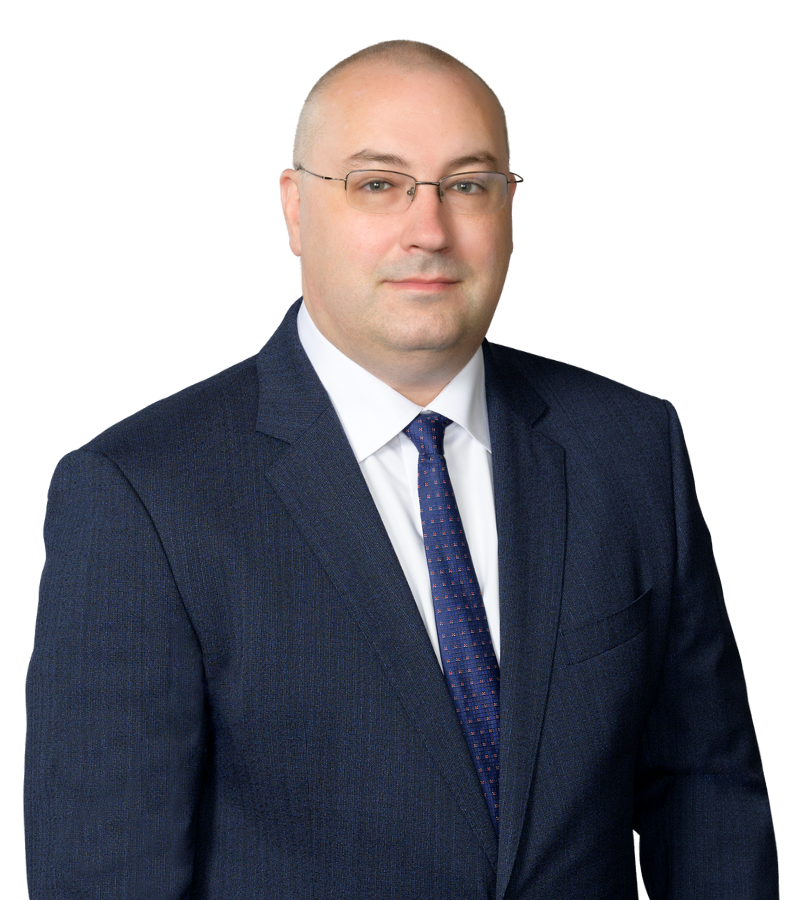 A photo of attorney John Slavik in a dark business suit and white dress shirt, wearing glasses